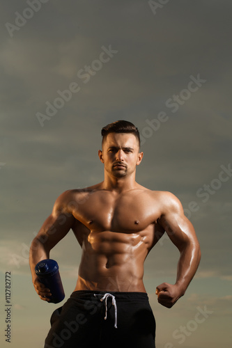 Wet muscular man with water bottle