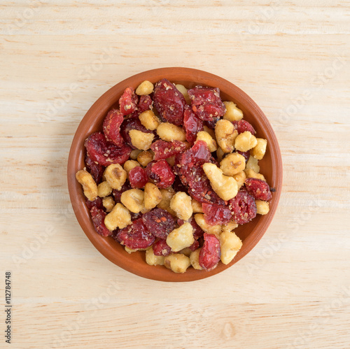 Cranberries and walnuts in a small bowl on a wood table top view.