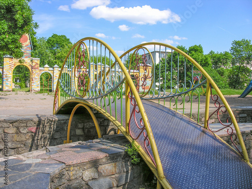 Декоративный мостик с ажурными перилами перекинут через чашу фонтана на детской площадке © charlyblr