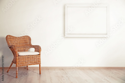 Cozy chair and picture frame on wall background