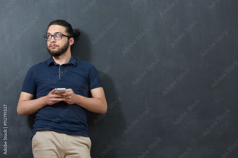picture of young arab man on chalkboard using phone picture of young arab man on chalkboard using phone