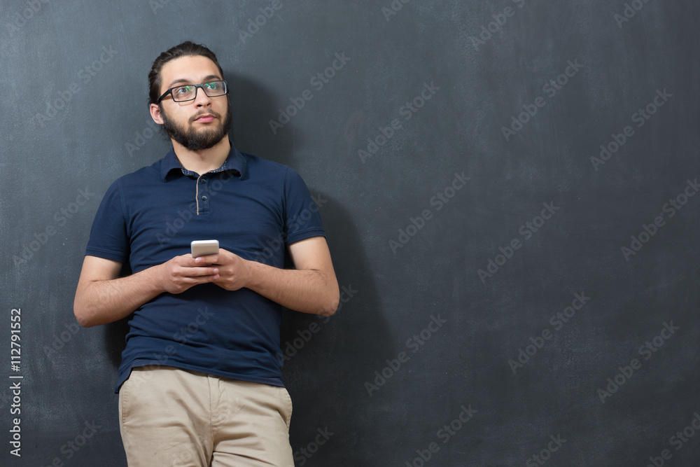 picture of young arab man on chalkboard using phone picture of young arab man on chalkboard using phone