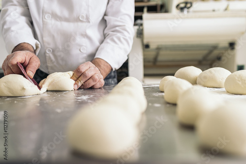 Foto Baker kneading dough in a bakery.