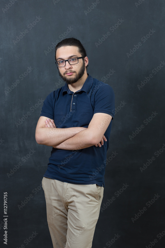 Attractive young man against blackboard.