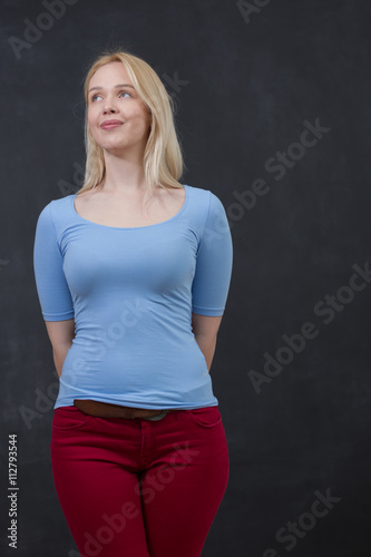 Portrait of a beautiful young blond woman leaning against a blac