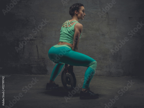 Female in a zure sportswear doing squats.