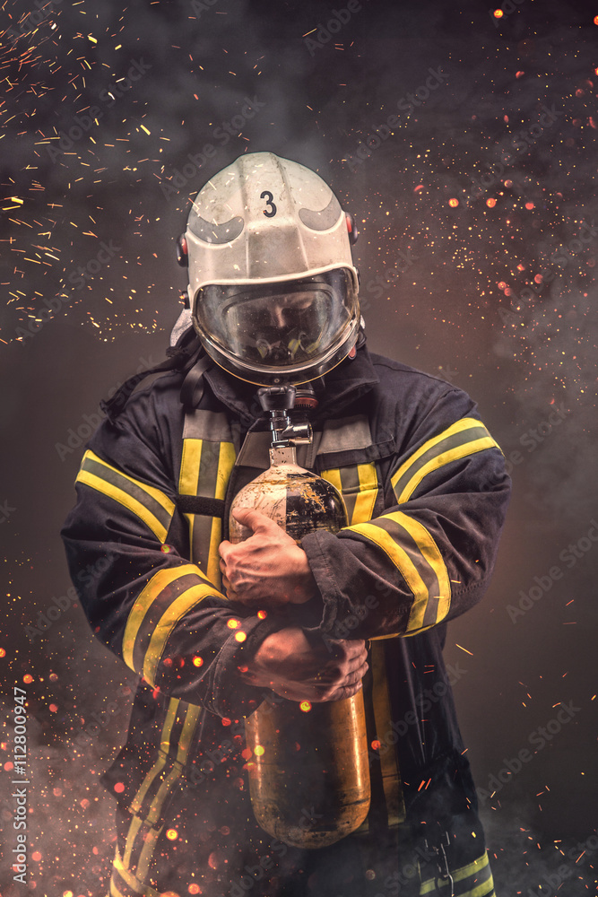 Fototapeta premium Firefighter in helmet and mask holds oxygen tanks.