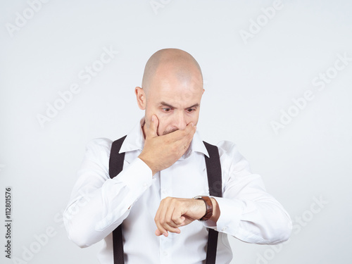 Bald businessman looks at his watch