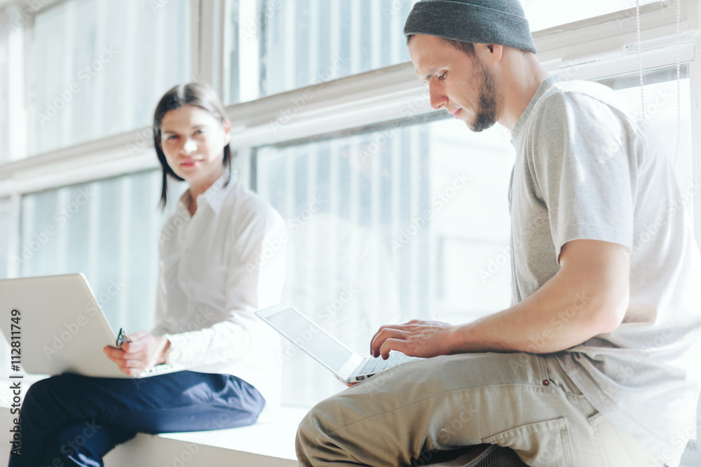 Obraz premium Man and woman working together in loft office with laptops