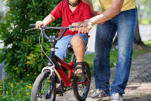 Father helping his son riding bicycle for the first time