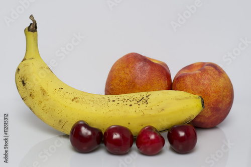 Banana,cherries and two peaches isolated on white background