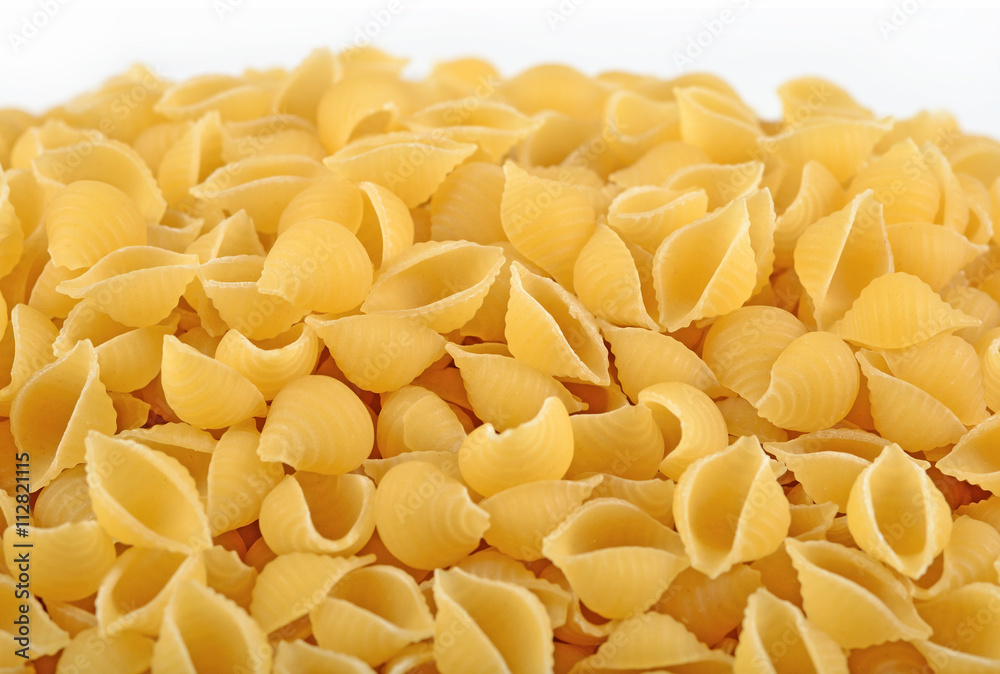 Heap of uncooked italian pasta shells on a white Heap of uncooked italian pasta shells on a white