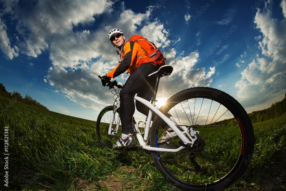biker in orange jersey riding on green summer field