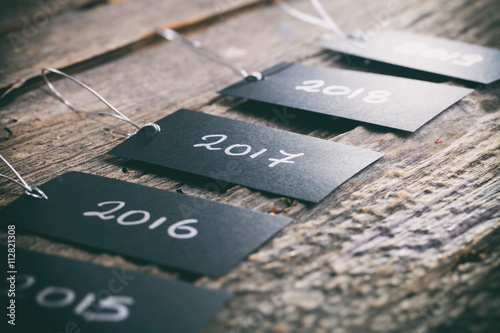 Pricing tags in a row with "2017" focus and other years text on wooden background