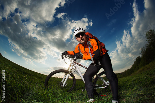 biker in orange jersey riding on green summer field