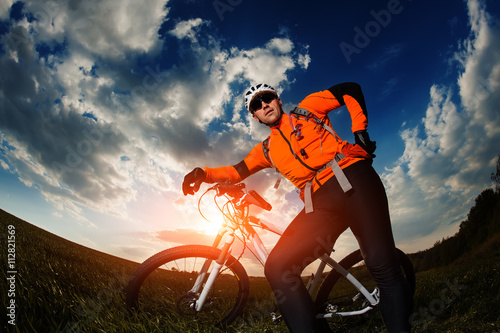biker in orange jersey riding on green summer field