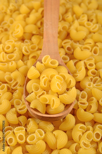 Uncooked italian pasta pipe rigate in a spoon