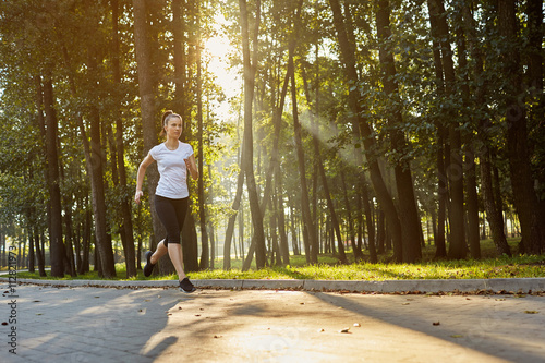 young woman running in park during sunny morning photo