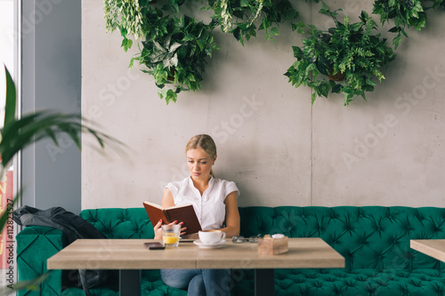 Enjoyoing coffee break. Woman reading book in cafeteria