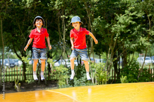 Two sweet children, boy brothers, jumping on a big trampoline © Tomsickova
