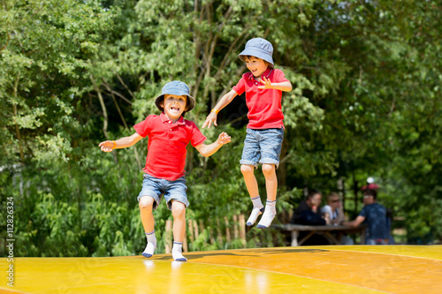 Two sweet children, boy brothers, jumping on a big trampoline