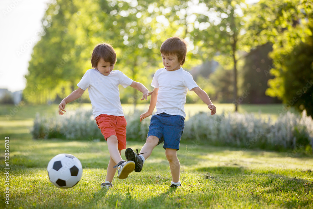 Two cute little kids, playing football together, summertime. Chi Two cute little kids, playing football together, summertime. Chi