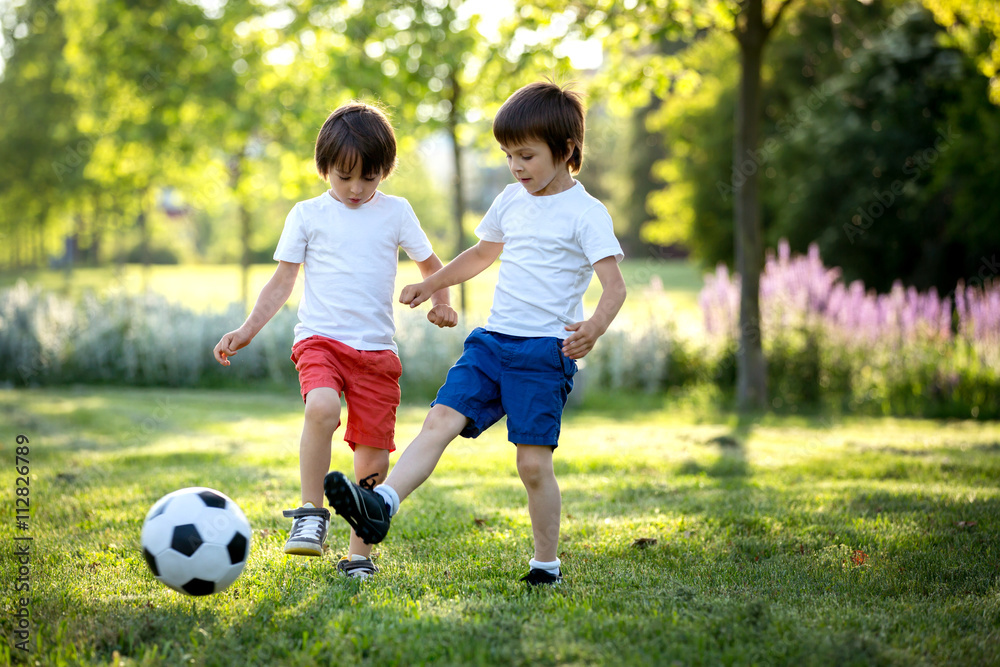 Two cute little kids, playing football together, summertime. Chi
