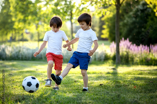Two cute little kids, playing football together, summertime. Chi