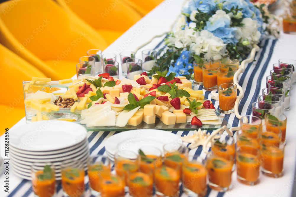 Fototapeta premium Beautifully decorated catering banquet table with different food snacks and appetizers with sandwich, caviar, fresh fruits on corporate christmas birthday kids party event or wedding celebration