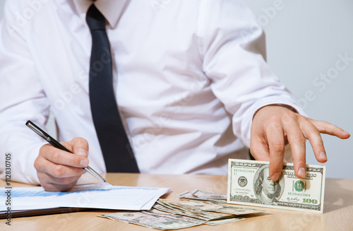 Businessman sitting at the table and holding money