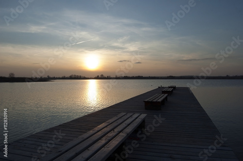 Pier with benches on a lake at sunset