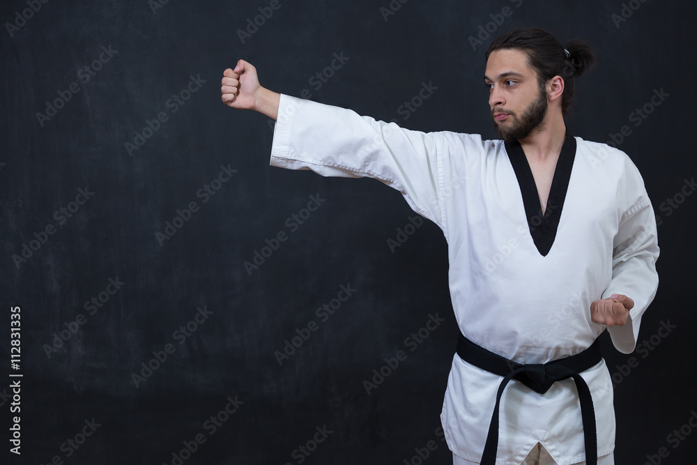 Fototapeta premium White Karate Fighter Isolated On Black With Copyspace