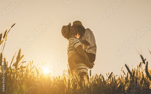 Young couple kissing on the background of a sunset in the wheat field photo