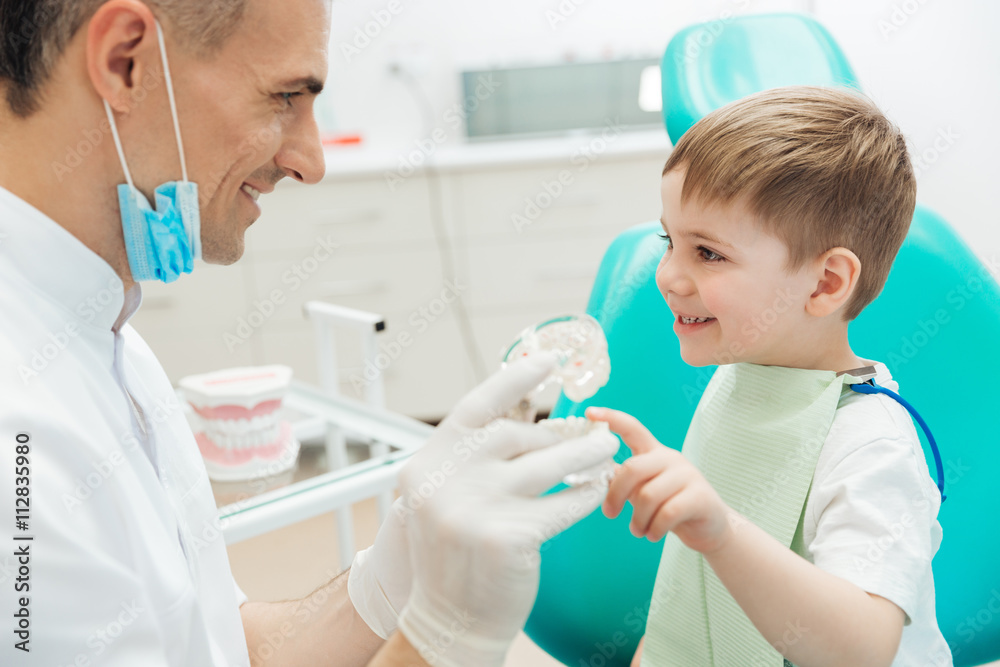 Cheerful man dentist demonstrating tooth brushing to little boy Cheerful man dentist demonstrating tooth brushing to little boy