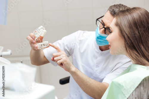 Bild auf Leinwand Man dentist show dentures teeth at dental surgery to patient