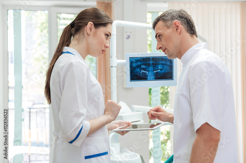 Two doctors dentists looking panoramic photo of teeth on monitor