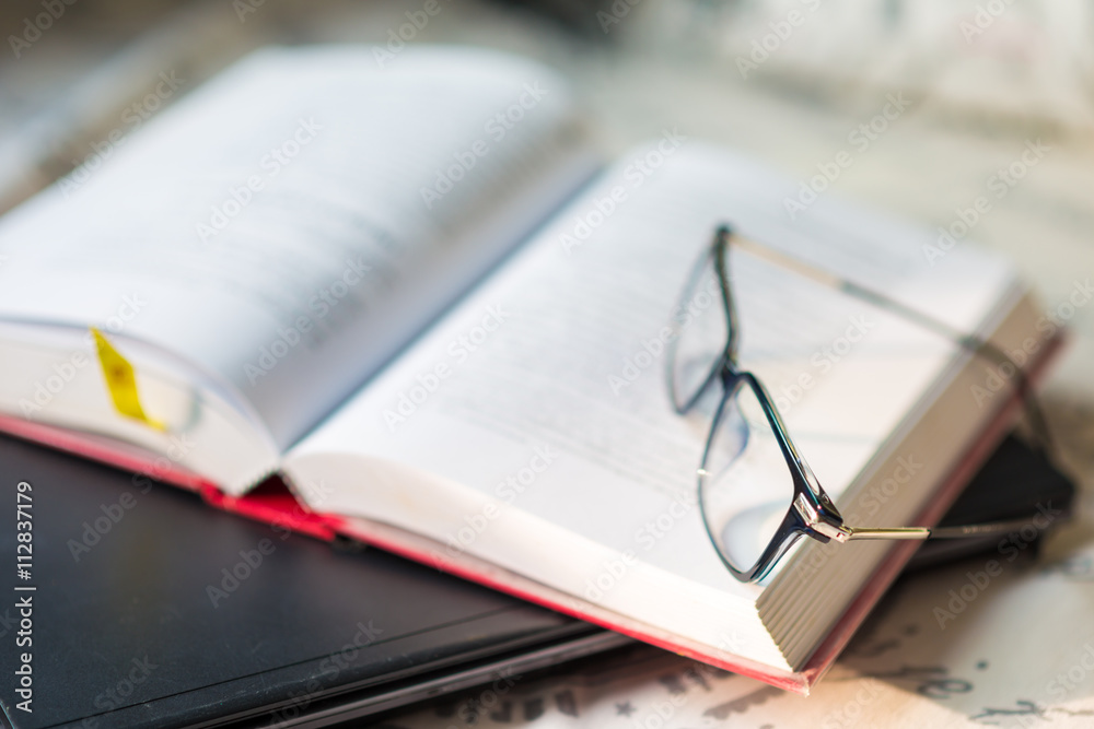 Books with a pair of glasses and computer laptop on bedroom Books with a pair of glasses and computer laptop on bedroom