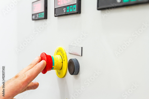 Hand, finger is pushing emergency red stop button photo