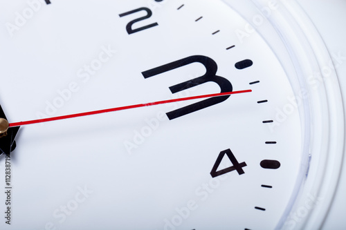 White wall clock with black arrows. Selective focus. Shallow dep