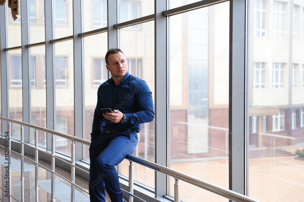 businessman looking through the phone by the window businessman looking through the phone by the window