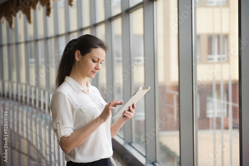 Young businesswoman talking on mobile phone while standing by wi Free Download Young businesswoman talking on mobile phone while standing by wi - GFXLoad