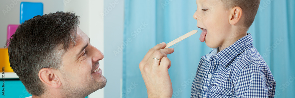 Obraz premium Pediatrician examining boy's throat