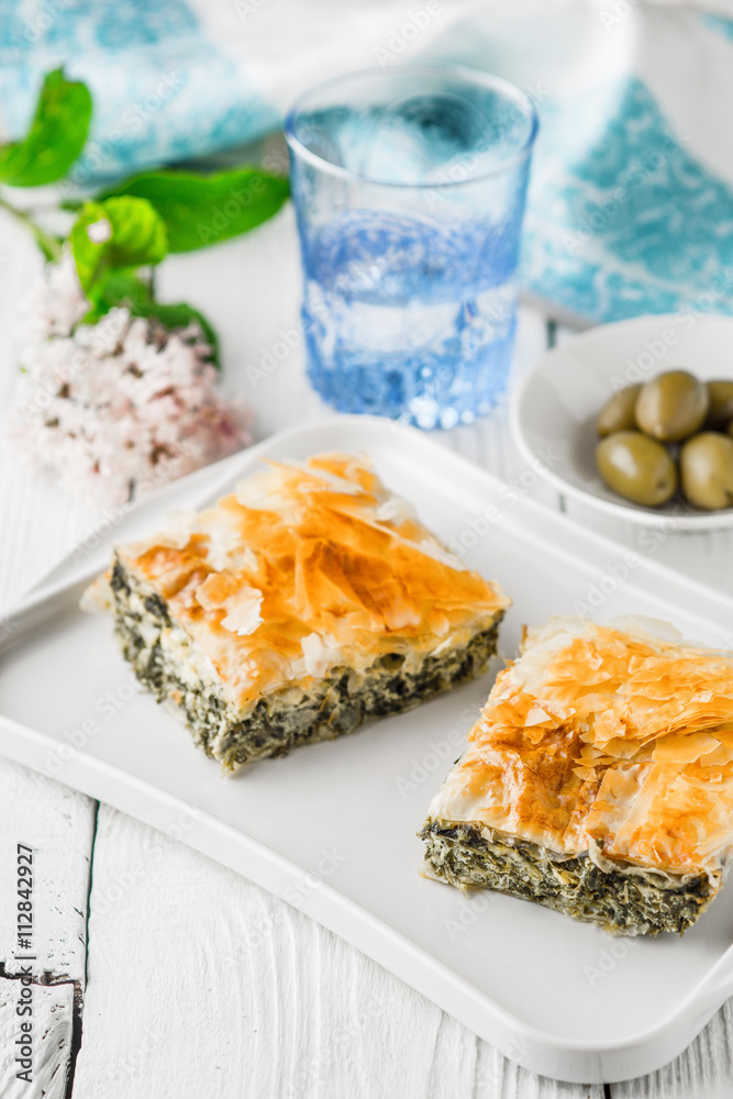Greek pie spanakopita on the white plate with accessorizes vertical Greek pie spanakopita on the white plate with accessorizes vertical