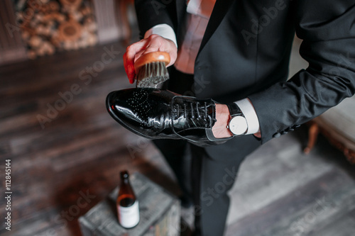 Cleaning shoes on wooden background. black shoe with a brush photo
