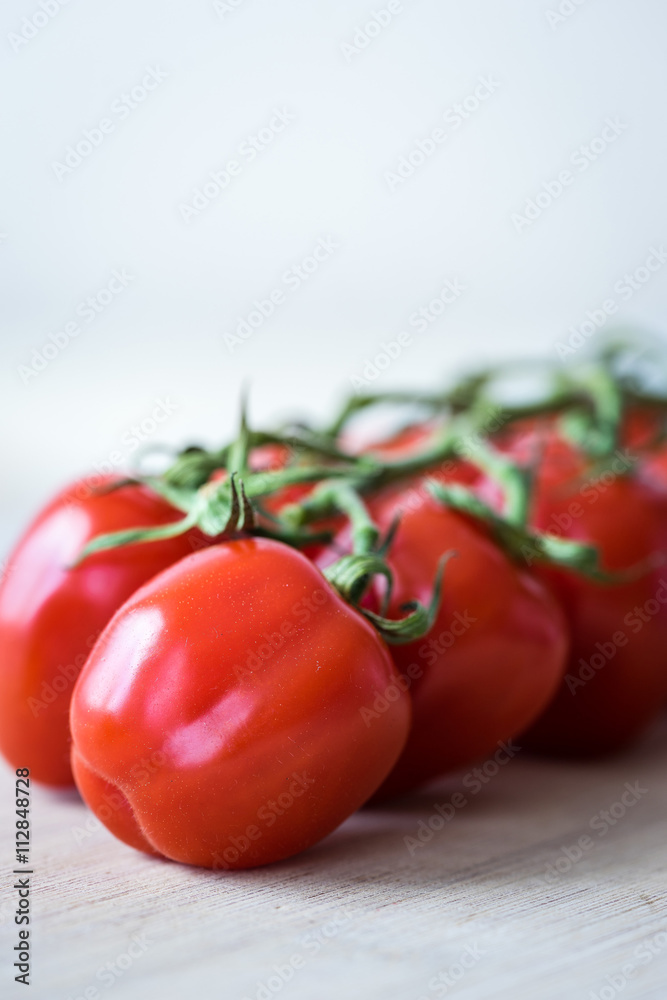 Vertical view of fresh tomatoes on a wooden desk. Marco shot of red tomatoes. Selective focus. Shallow depth of field. Vertical view of fresh tomatoes on a wooden desk. Marco shot of red tomatoes. Selective focus. Shallow depth of field.