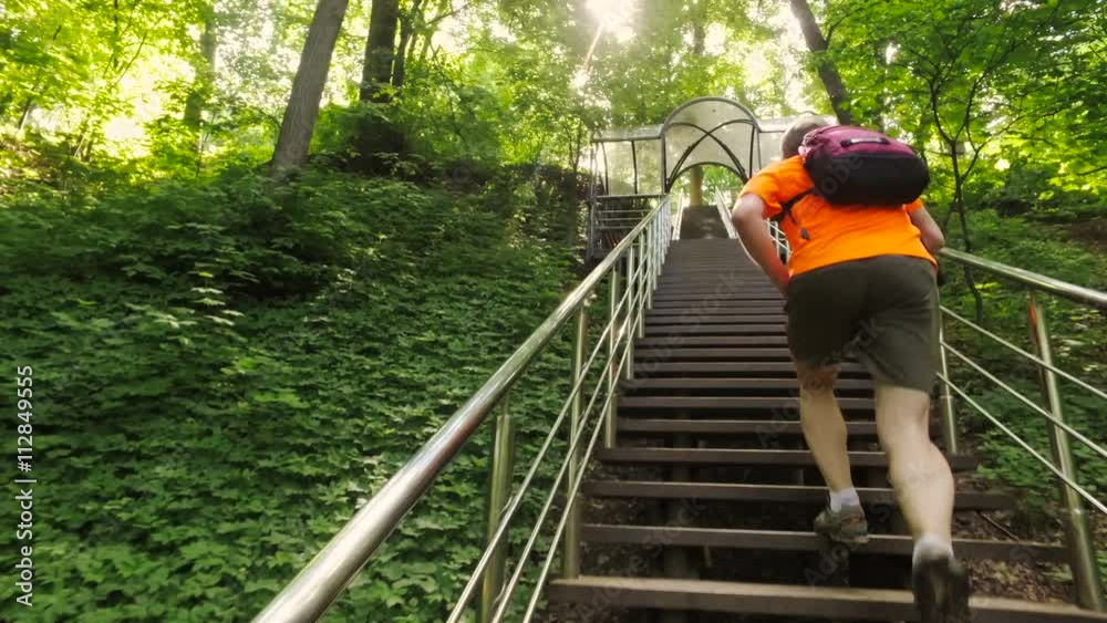 Adult man running jogging up the stairs outdoors in a forest nature on a forest trail Adult man running jogging up the stairs outdoors in a forest nature on a forest trail