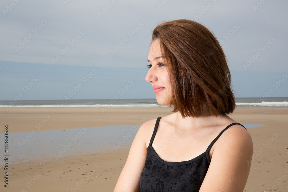 Thoughtful young woman looking away with sea in background Thoughtful young woman looking away with sea in background