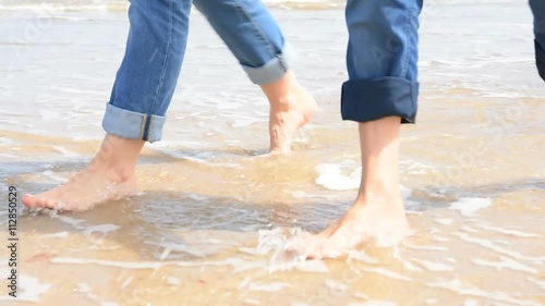Closeup of people's feet walking on sandy beach photo