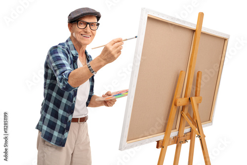 Joyful mature artist painting on a canvas