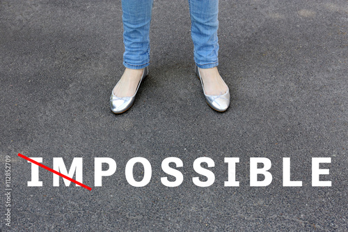 Changing the word impossible to possible on asphalt road with feet © Africa Studio
